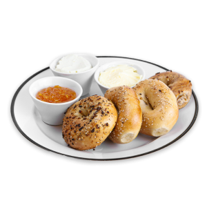 Bagels on a white plate with cream cheese, butter and jelly
